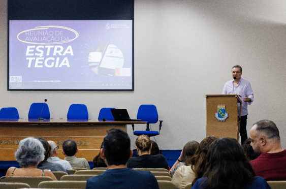 Auditório da Reitoria, com tela com apresentação ao fundo, Pró-reitor de Planejamento e Administração apresentando no lado direito, e diversos servidores assistindo
